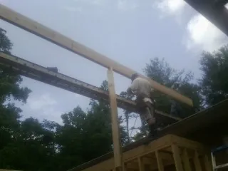 Carpenter setting a ridge beam over a new addition frame — Ice Dam Removal by Roofing Brothers in Gay