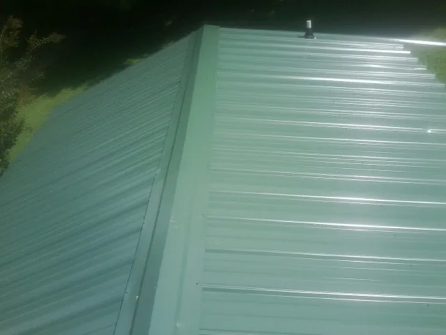New green metal panels meeting at the ridge of a roof — Flat Roof Repair work by our crew in Gay