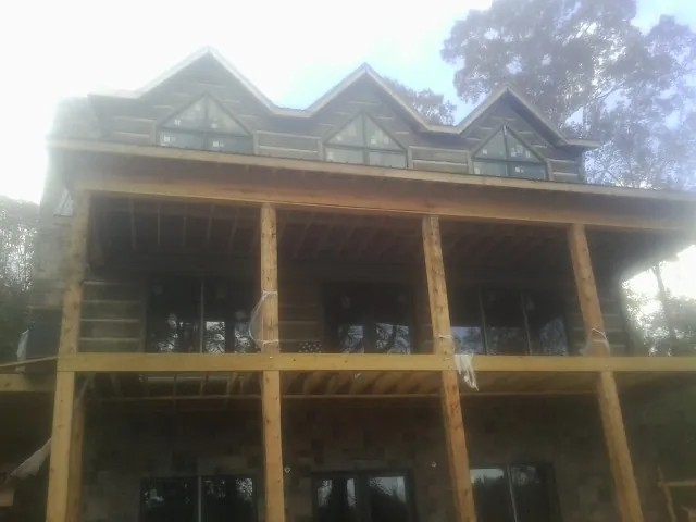 Dormers and porch framing on a large log home under construction — Roof Coating work by our crew in Gay