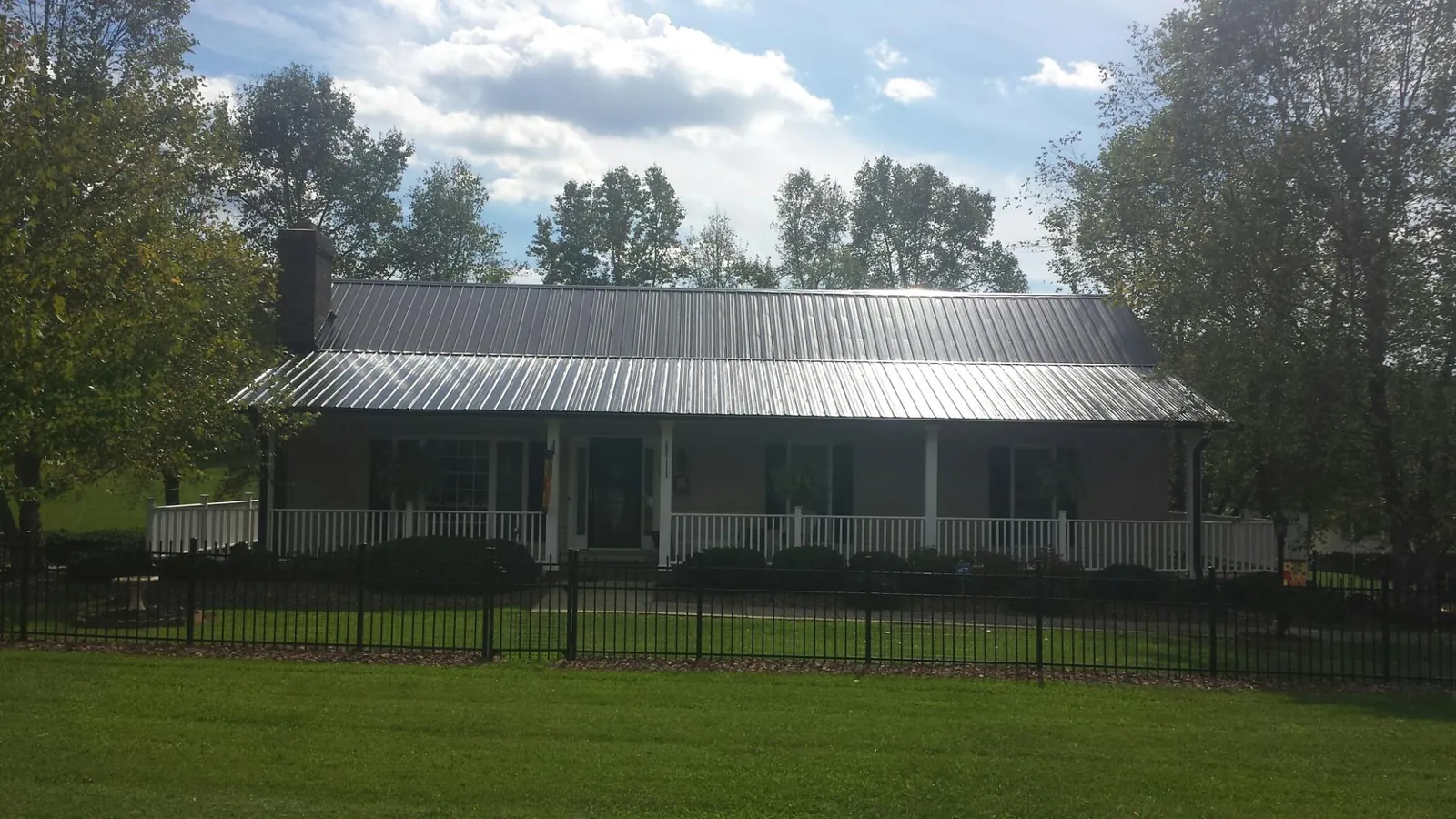 Gray metal roof on a brick ranch with a full width front porch — Gutter Guard Installation work by our crew in Gay