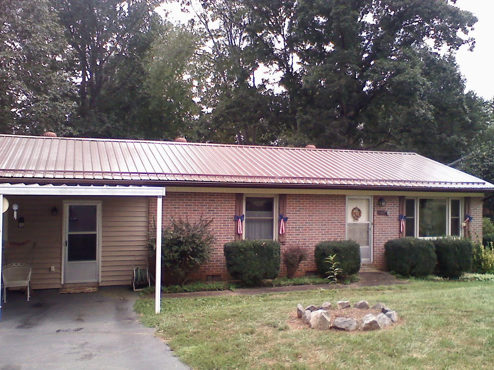 Bronze metal roof and carport on a brick ranch home — Roof Repair work by our crew in Gay